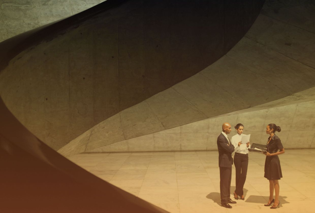 A man and two woman standing inder a staircase